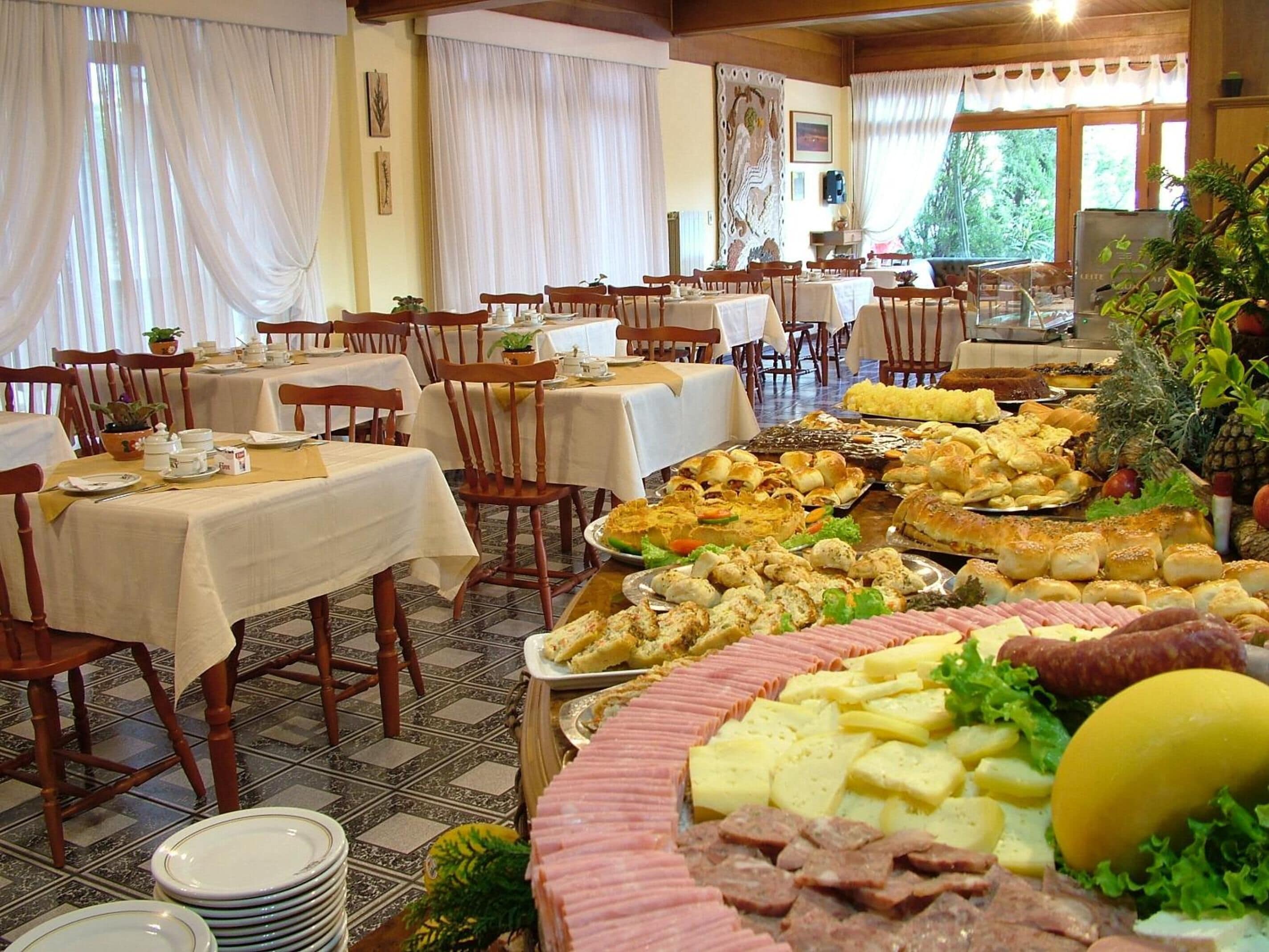 A buffet-style dining area with multiple tables and chairs, featuring a variety of food items and a large centerpiece.