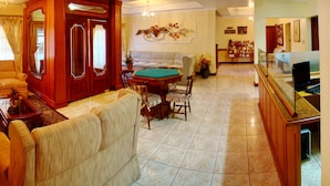 A spacious living room with a sofa, armchairs, a coffee table, and a dining area with a table and chairs. - Hotel Sky (Gramado)