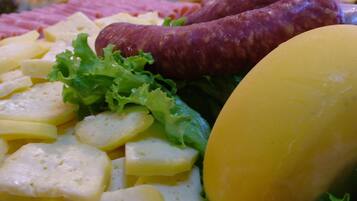 Una tabla de embutidos con diversos quesos, carnes y vegetales.