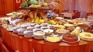 A buffet with a variety of food items and a centerpiece with fruits and plants. - Hotel Sky (Gramado)