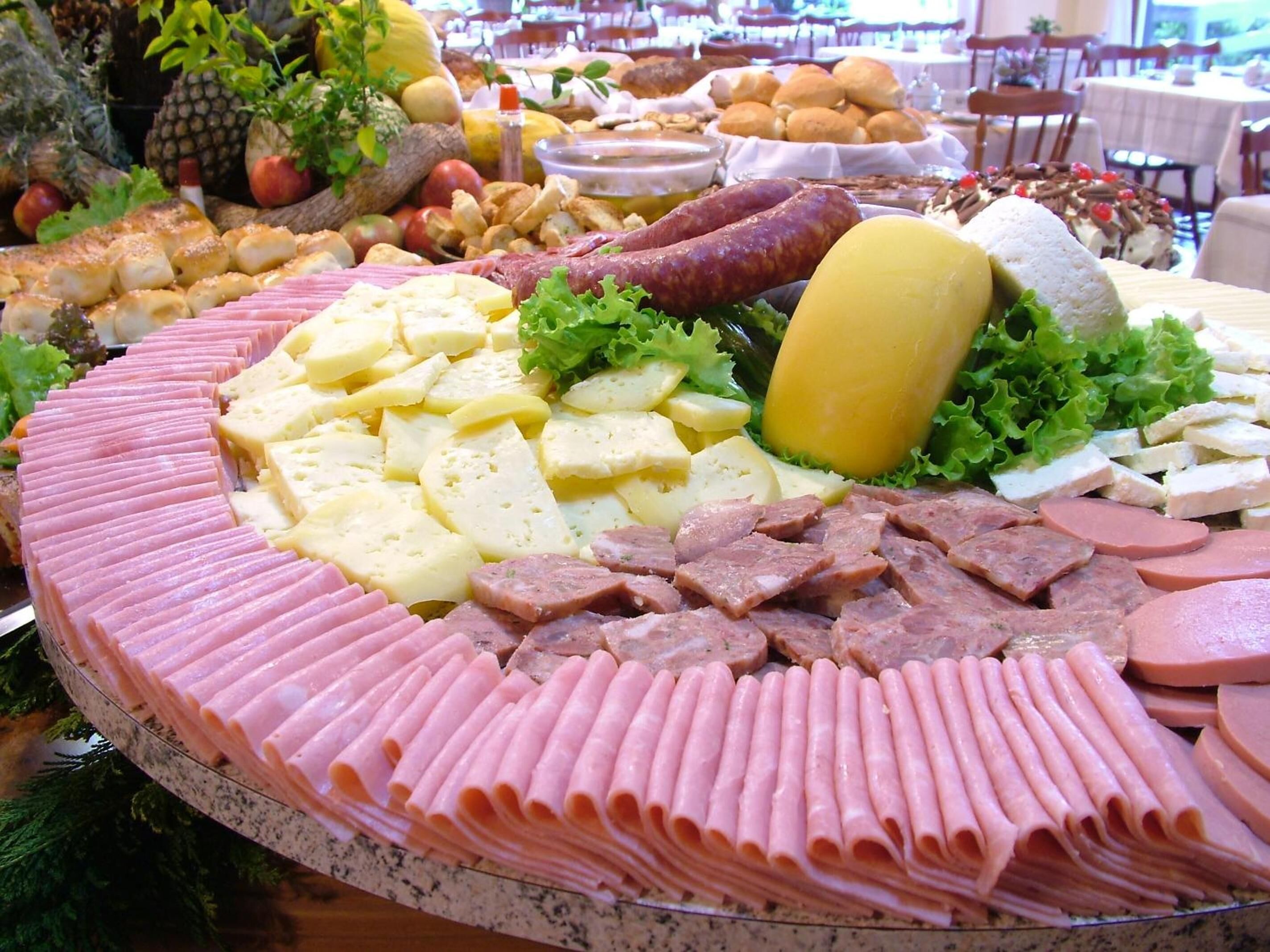 A buffet with various meats, cheeses, and fruits.