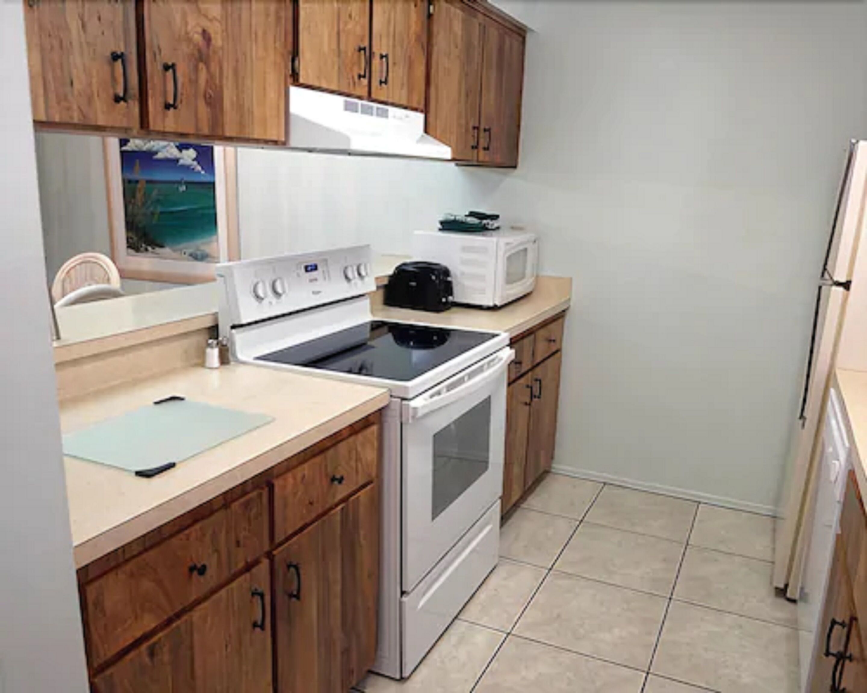 A kitchen with wooden cabinets, a stove, a microwave, and a refrigerator.