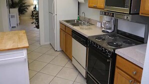 A kitchen with wooden cabinets, a refrigerator, a microwave, a stove, and a dishwasher. - Vacation Villas (Titusville)