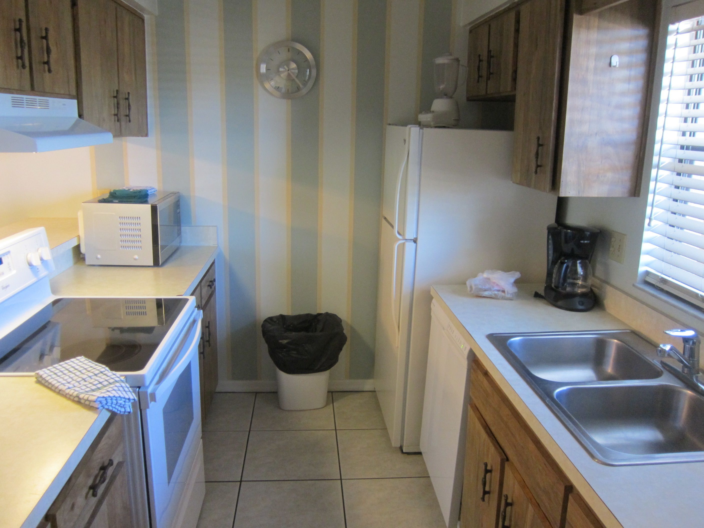 A kitchen with a microwave, stove, refrigerator, and a coffee maker.