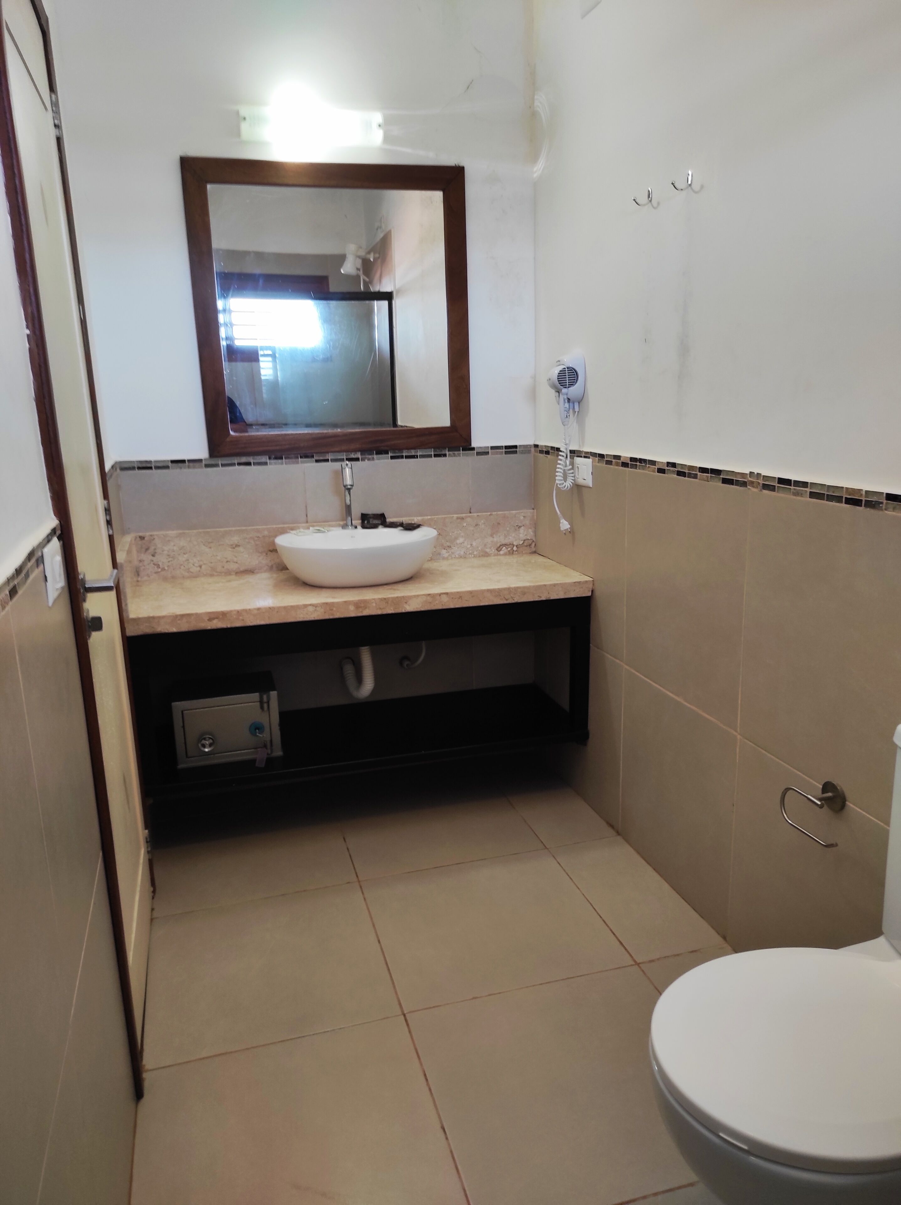 A small bathroom with a white sink, a mirror, a hairdryer, and a toilet.