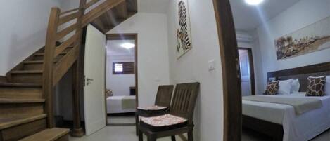 A bedroom with a bed, a chair, and a staircase.