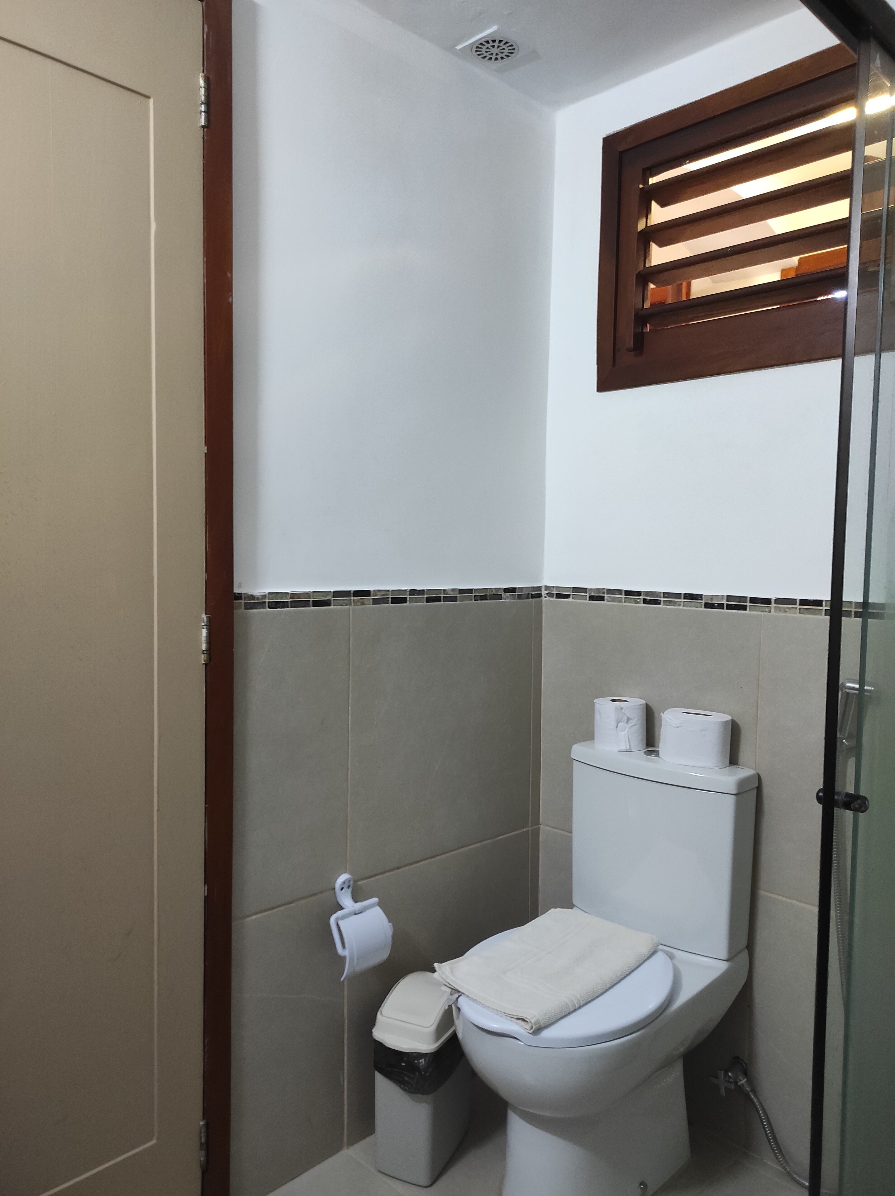 Casa de banho com sanita, um caixote de lixo e zona de duche.