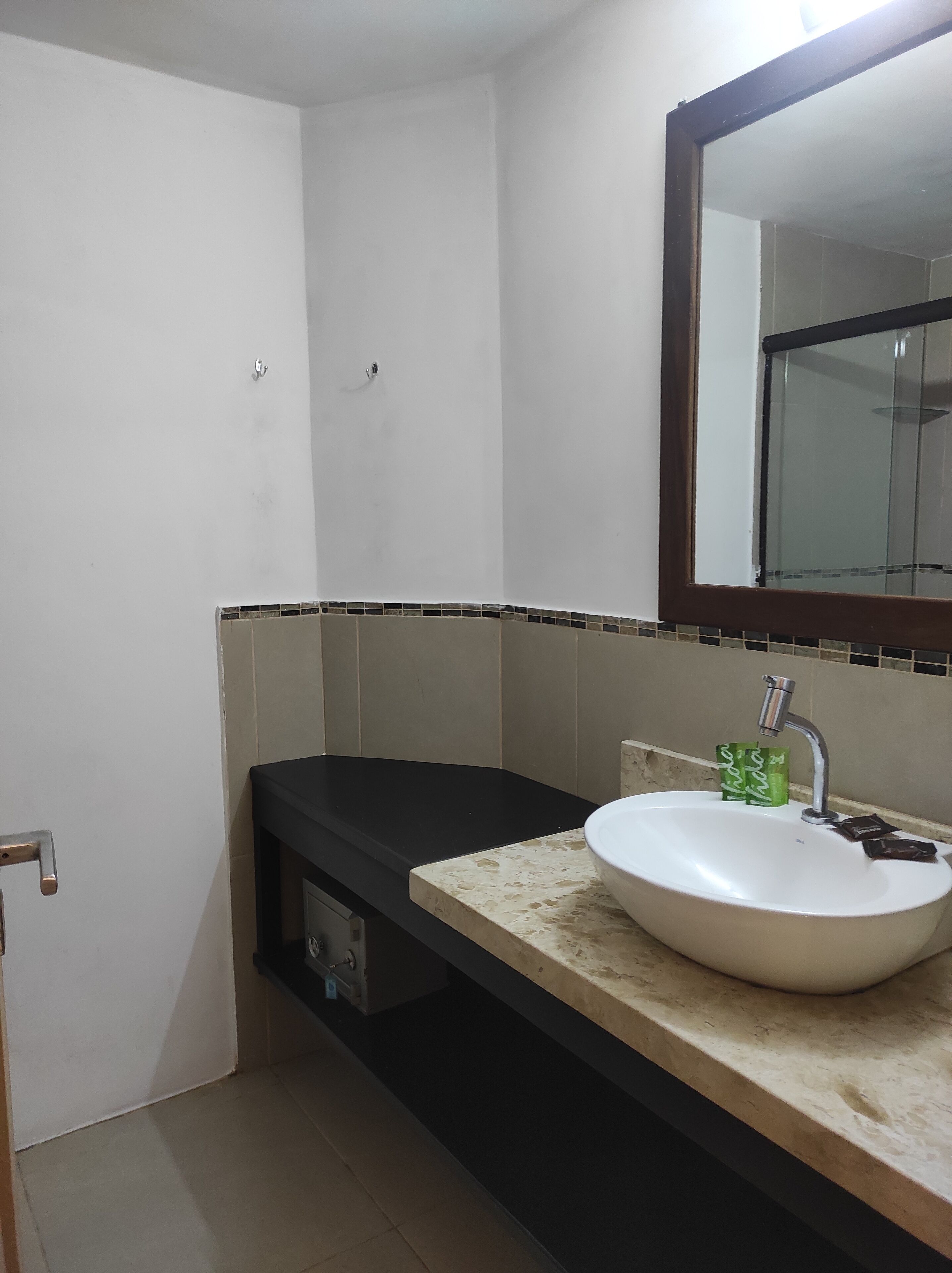 Un baño con lavamanos blanco, un espejo y encimera negra.
