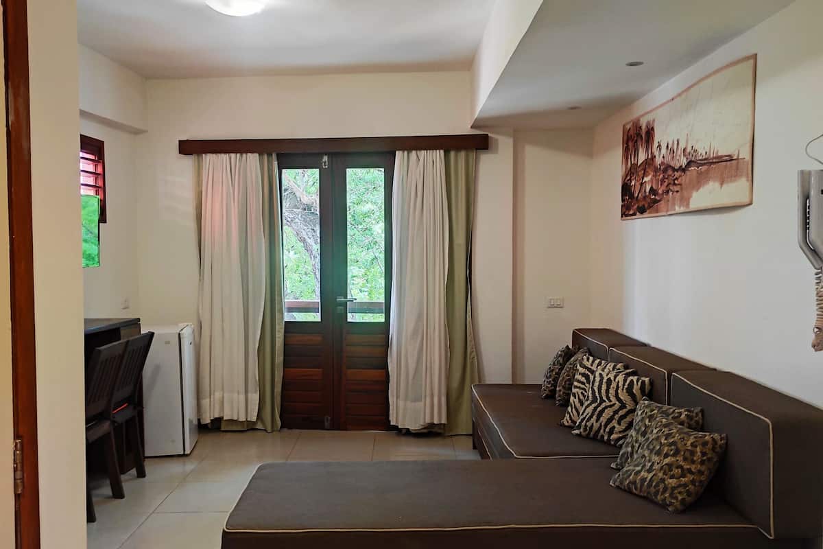 Una sala de estar moderna con un sofá, un comedor con mesa y sillas, y vistas a través de un ventanal.