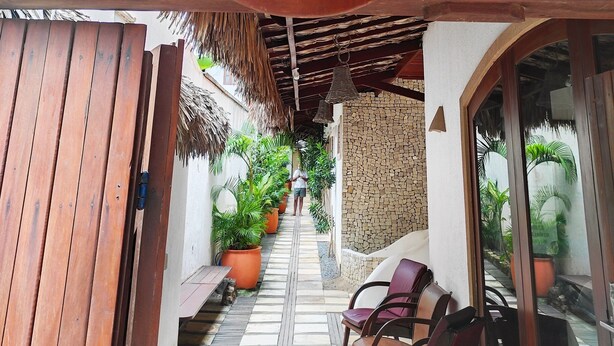 A covered outdoor area with a thatched roof, a wooden bench, and potted plants. - Hotel São Francisco (Jijoca de Jericoacoara)