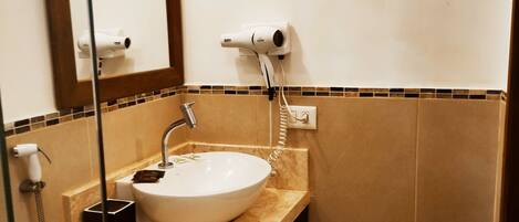 Un baño con lavamanos blanco, espejo, secador de pelo y toallero.