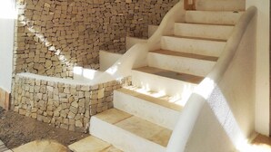 A staircase with a stone wall on one side and a white wall on the other, leading to an upper floor. - Hotel São Francisco (Jijoca de Jericoacoara)