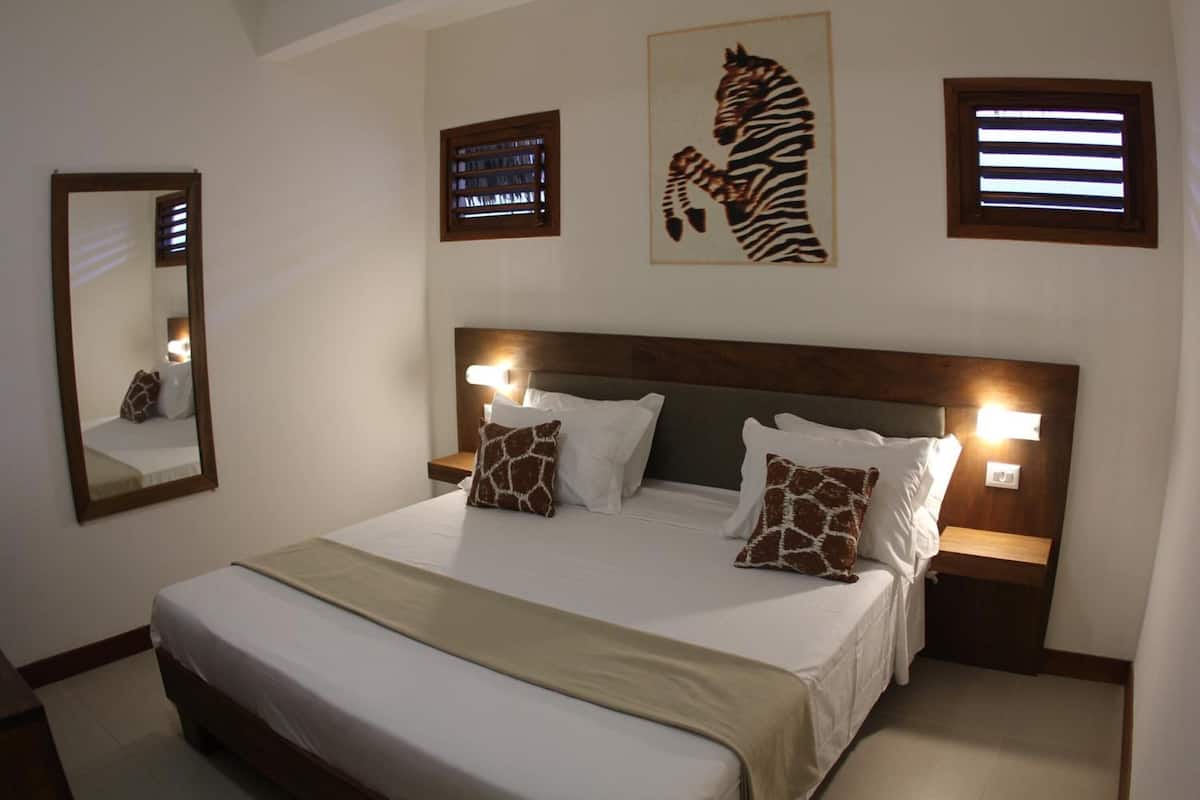 Una habitación de hotel con una cama grande, dos mesitas de noche, un espejo y obras de arte en las paredes.