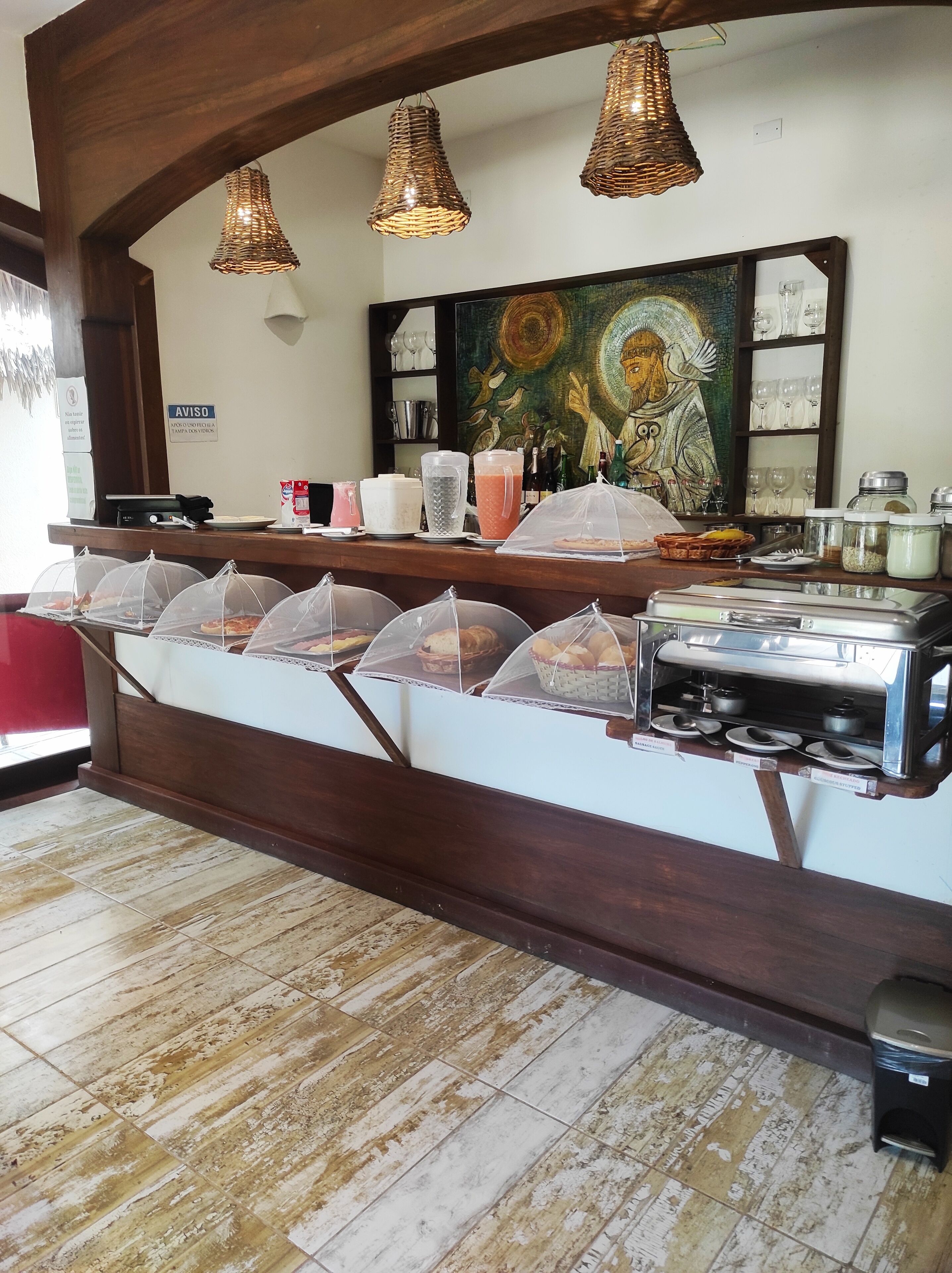 A buffet area with covered food stations, a painting on the wall, and a wooden counter.
