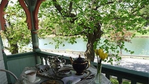 Une table dressée avec un service à thé, un vase rempli de fleurs jaunes et une vue sur un lac.