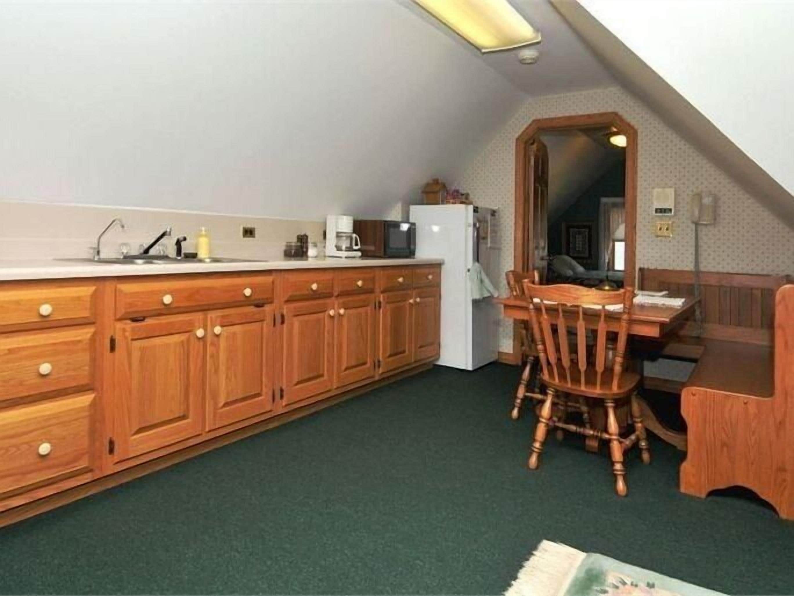 Une cuisine de taille réduite avec des meubles de rangement en bois, une table à manger avec des chaises et un réfrigérateur.