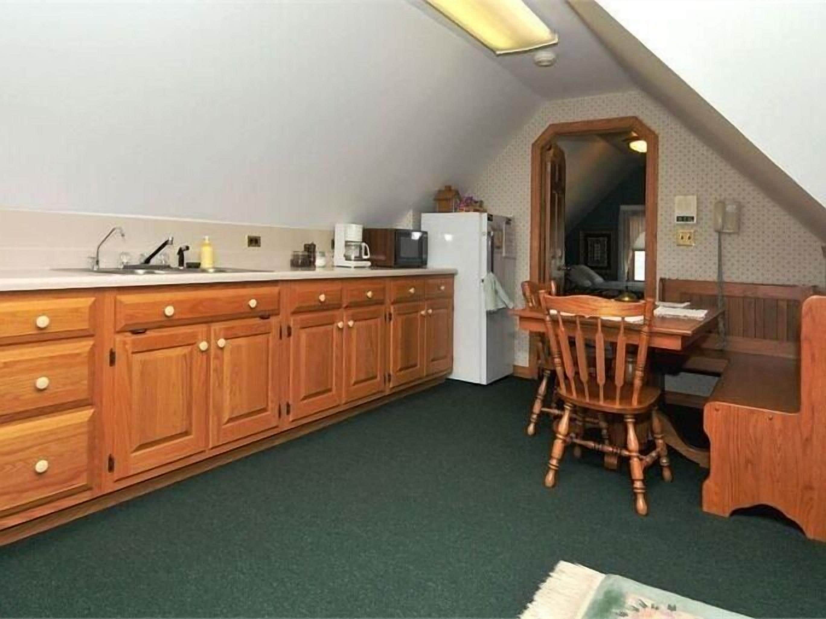 A compact kitchen with wooden cabinets, a dining table, and a refrigerator.