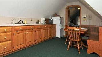 A compact kitchen with wooden cabinets, a dining table, and a refrigerator.