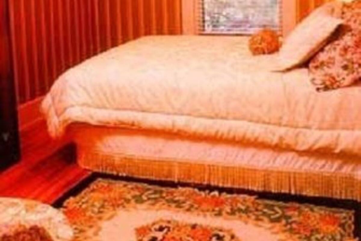 Quarto com uma cama grande, papel de parede listrado, um candelabro e uma janela com cortinas.