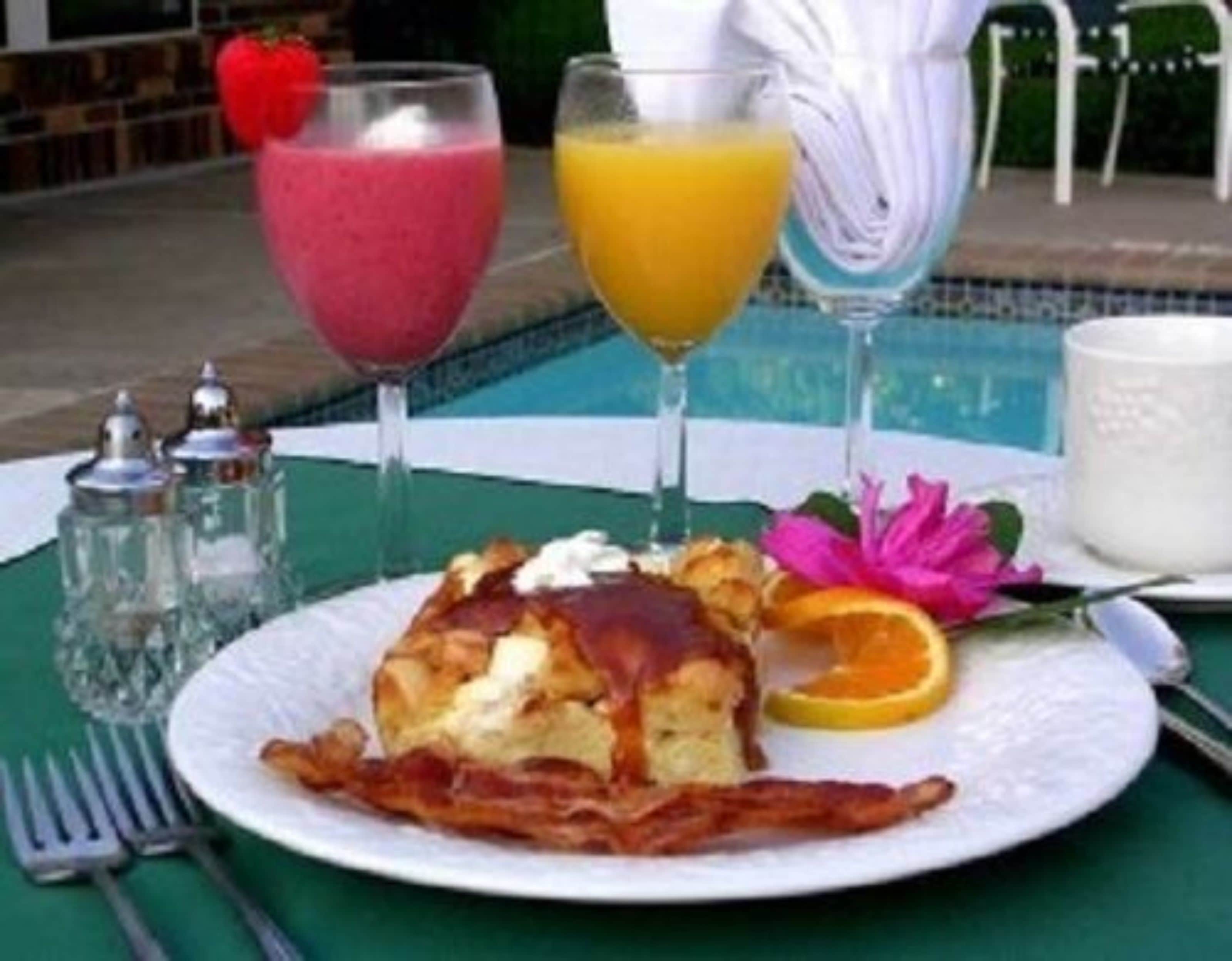 Une assiette de petit-déjeuner avec du bacon, un fruit et une boisson.