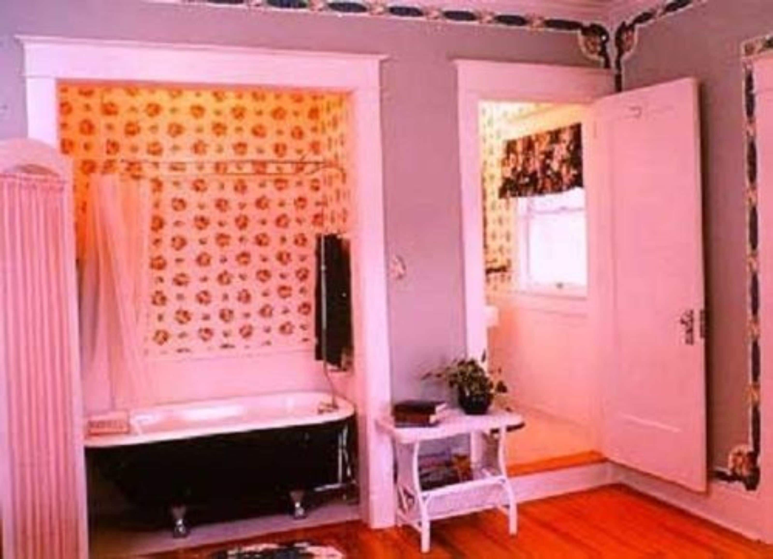 A bathroom with a bathtub, a white sink, and a small table with a plant.