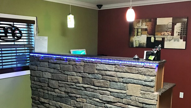 Zona de recepción con pared de piedra, felpudo, escritorio, computadora y lámpara colgante.