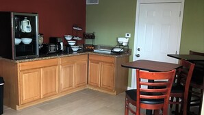 Una cocina compacta con armarios de madera, un refrigerador y una mesa de comedor con sillas.