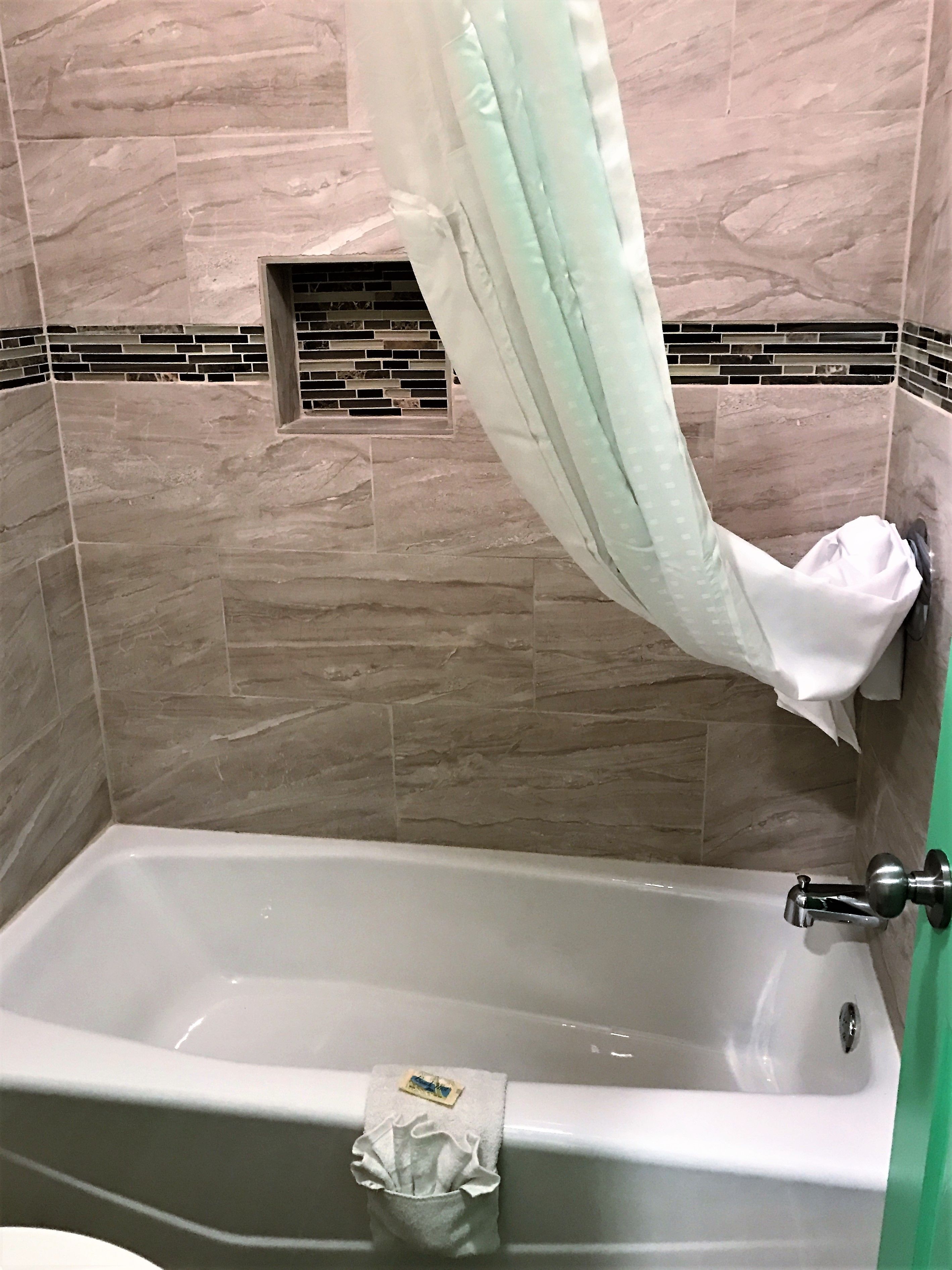 A bathroom with a bathtub, a shower curtain, and a towel rack.