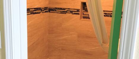 A bathroom with a bathtub, a shower curtain, and a tiled wall.