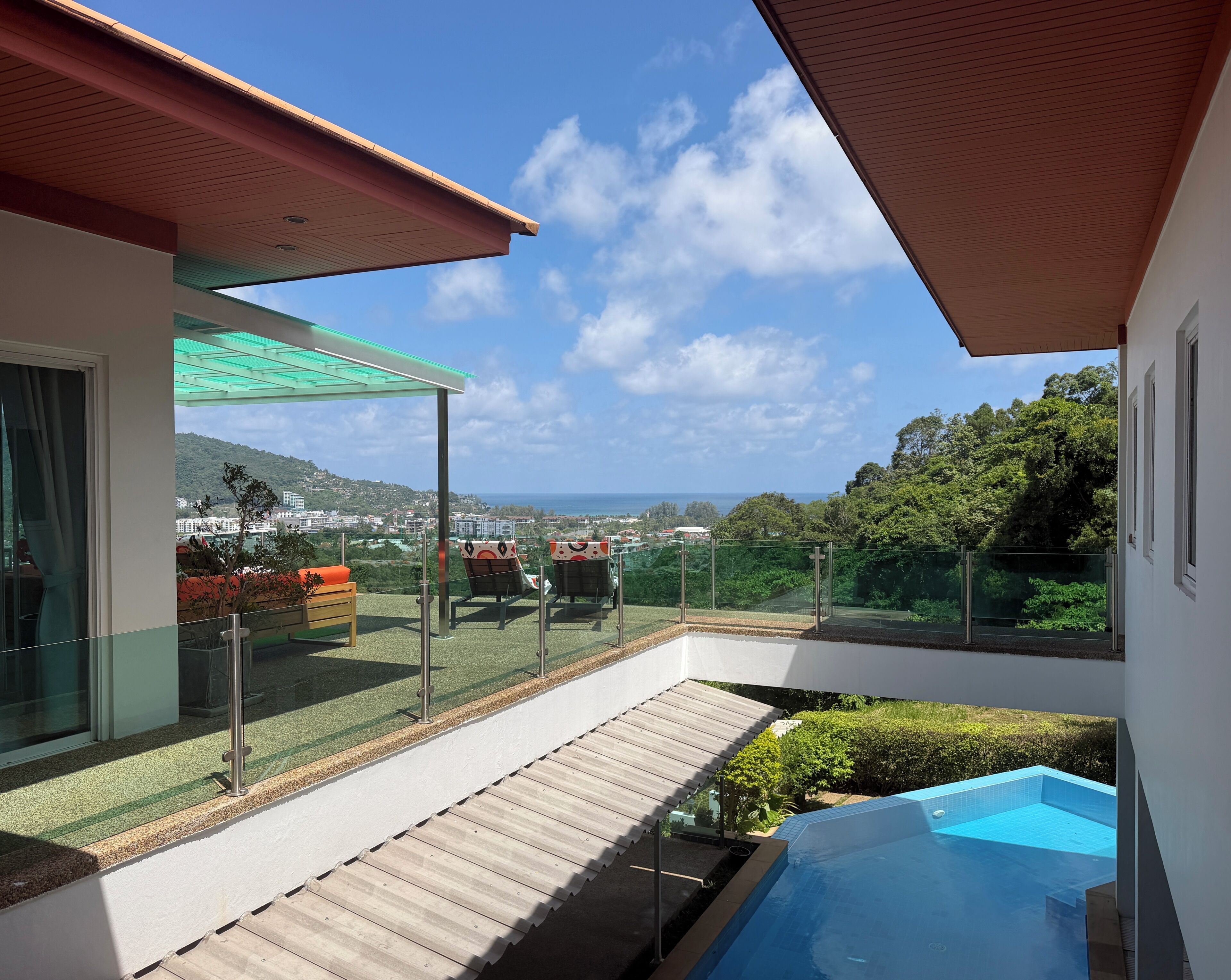 Ein moderner Balkon mit Glasgeländer, einer Holzterrasse und einem Pool.