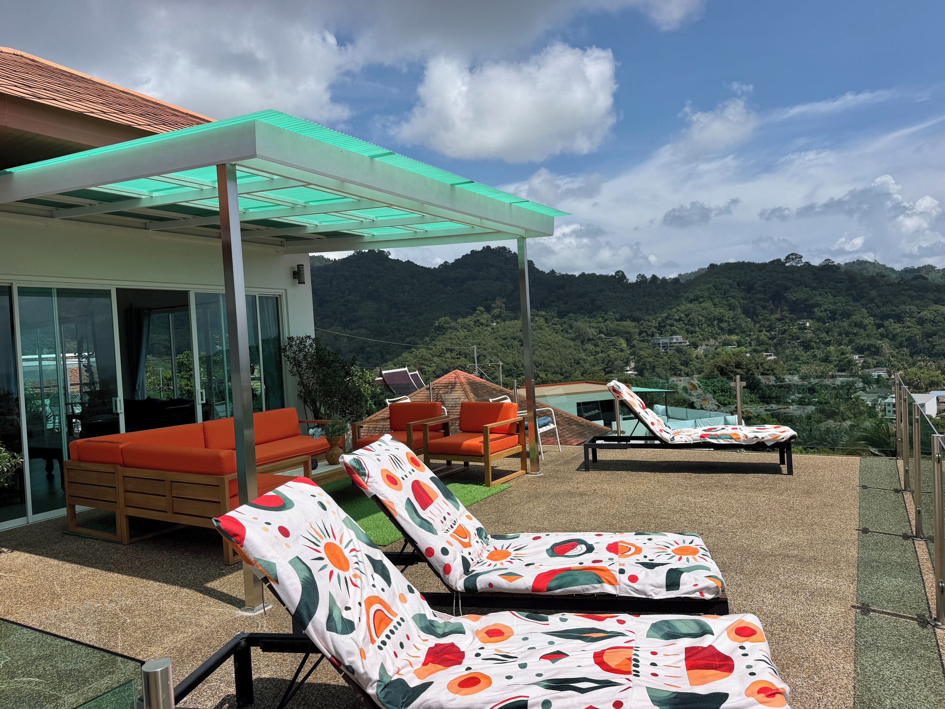 A rooftop terrace with lounge chairs, a sofa, and a covered seating area.