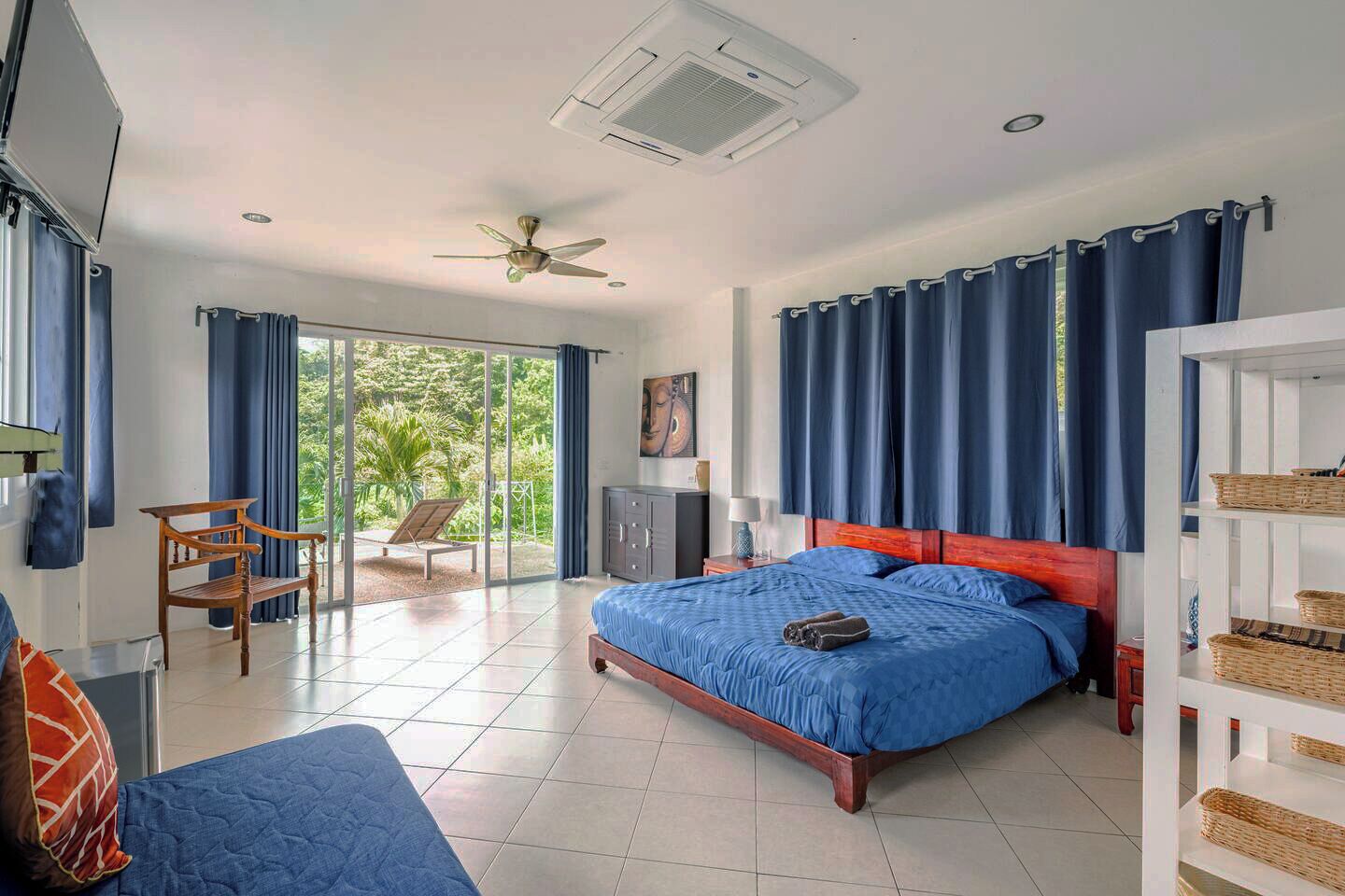 A bedroom with a bed, a chair, a desk, and a view of the outdoors.