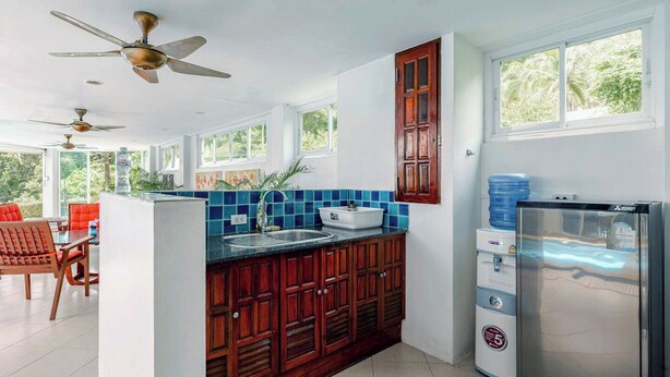 A kitchen with wooden cabinets, a sink, a refrigerator, and a water dispenser. - Kamala Heights (Kamala)