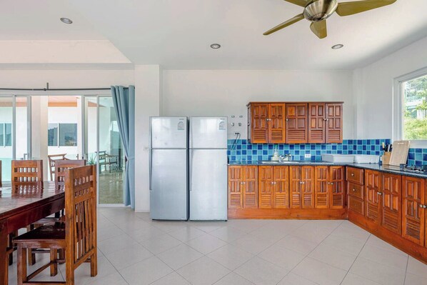 Una cocina moderna con armarios de madera, un refrigerador de acero inoxidable y un comedor con mesa y sillas.