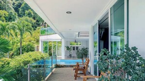 Un balcó amb piscina, mobles de fusta i vegetació abundant.