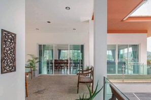 A modern interior with a dining area, large windows, and a balcony.