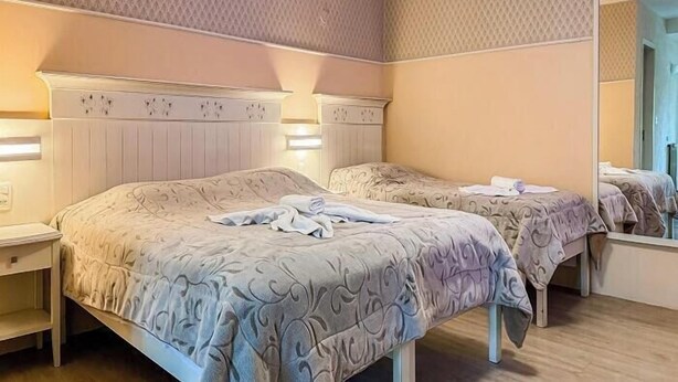 A hotel room with two beds, a nightstand, and a mirror. - Hotel Pousada Ald'Mama (Gramado)