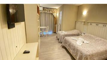 Una habitación de hotel con dos camas, televisión, escritorio y una silla.