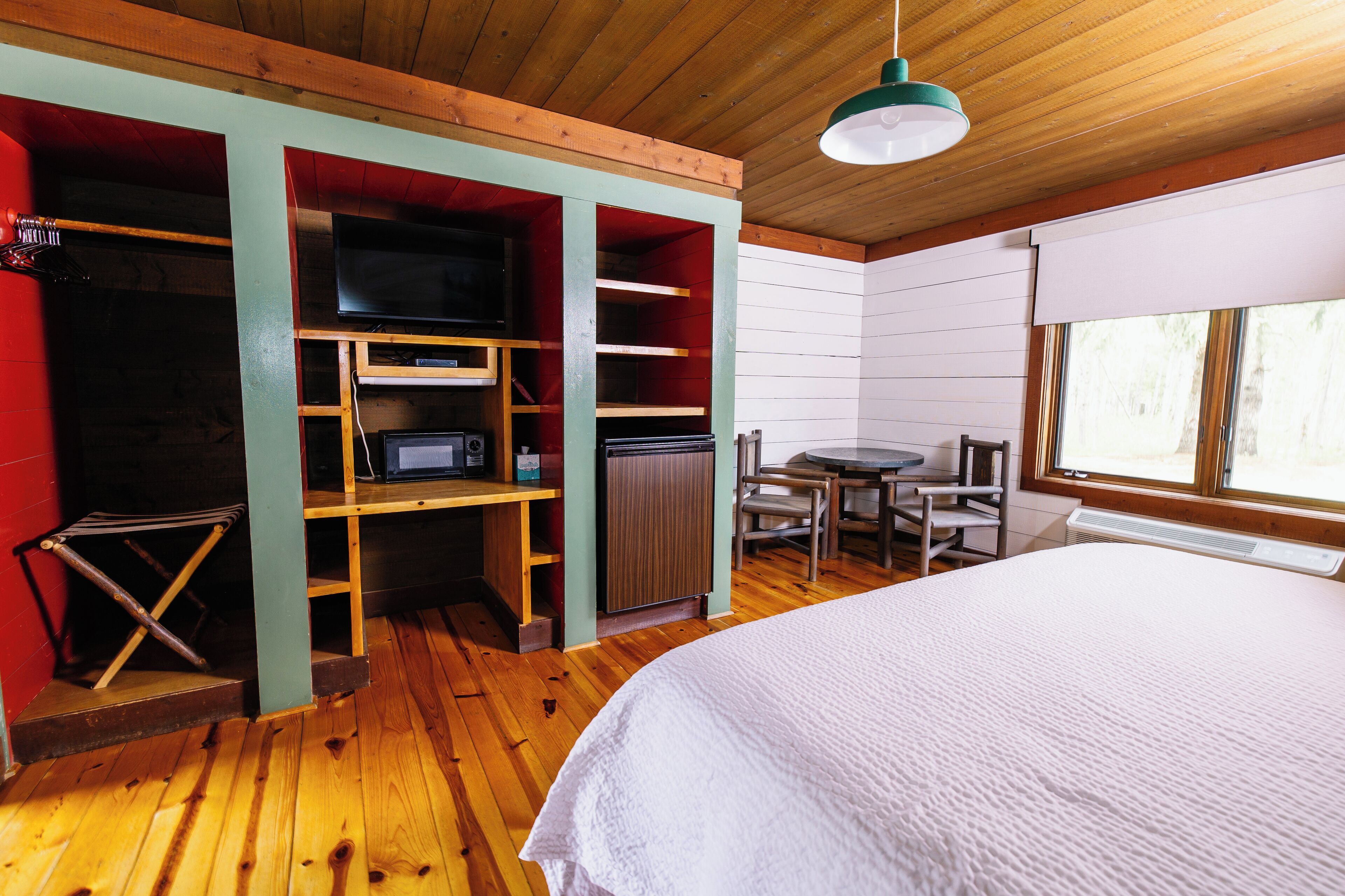 Una habitación acogedora con una cama, un escritorio con computadora, un televisor y una kitchenette pequeña.