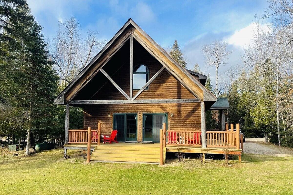 A wooden cabin with a sloped roof, a covered porch, and a large window.