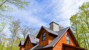 A wooden cabin with a deck, large windows, and a chimney. - Drummond Island Resort (Drummond Island)