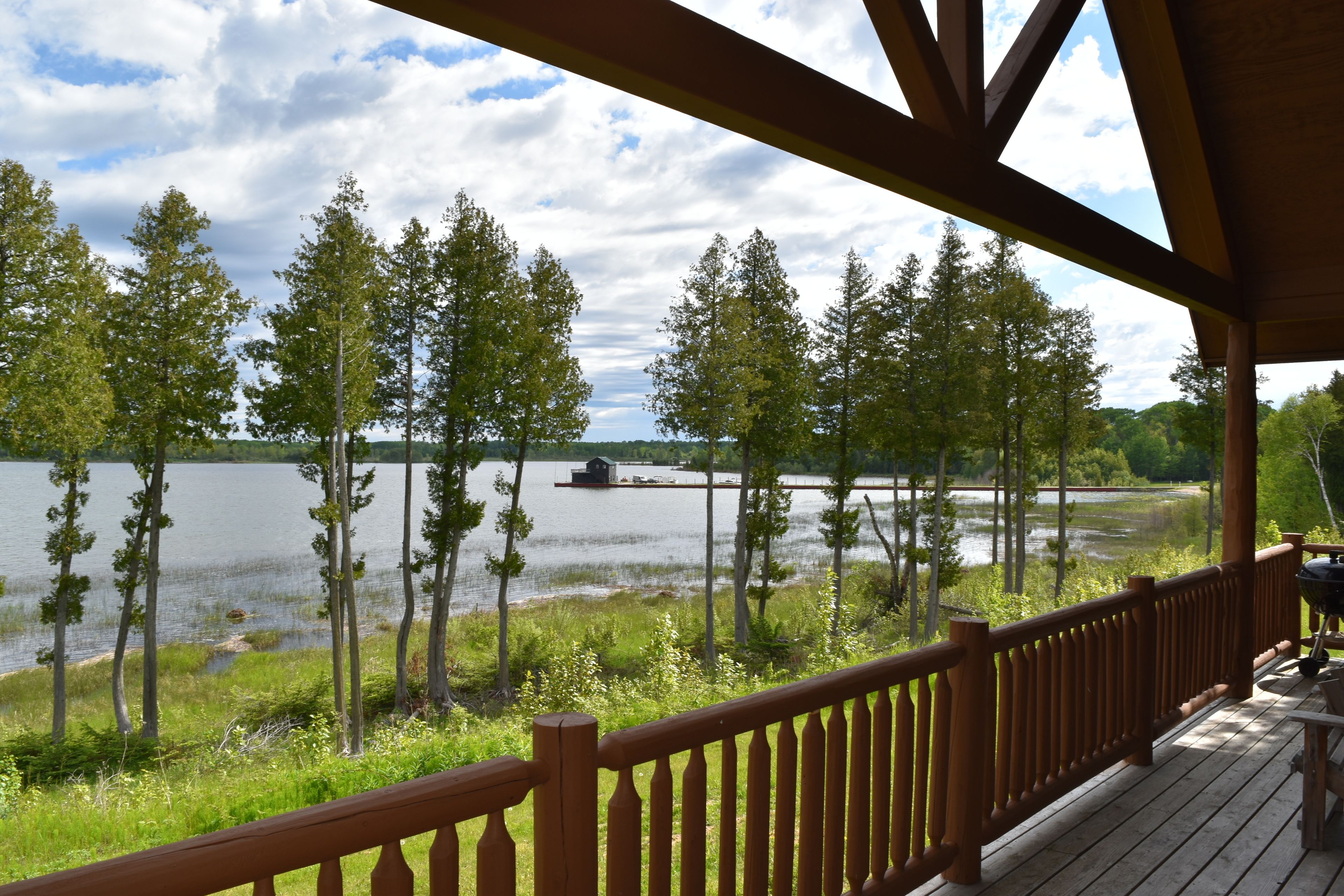 Eine Holzterrasse mit Blick auf einen See und Bäume.