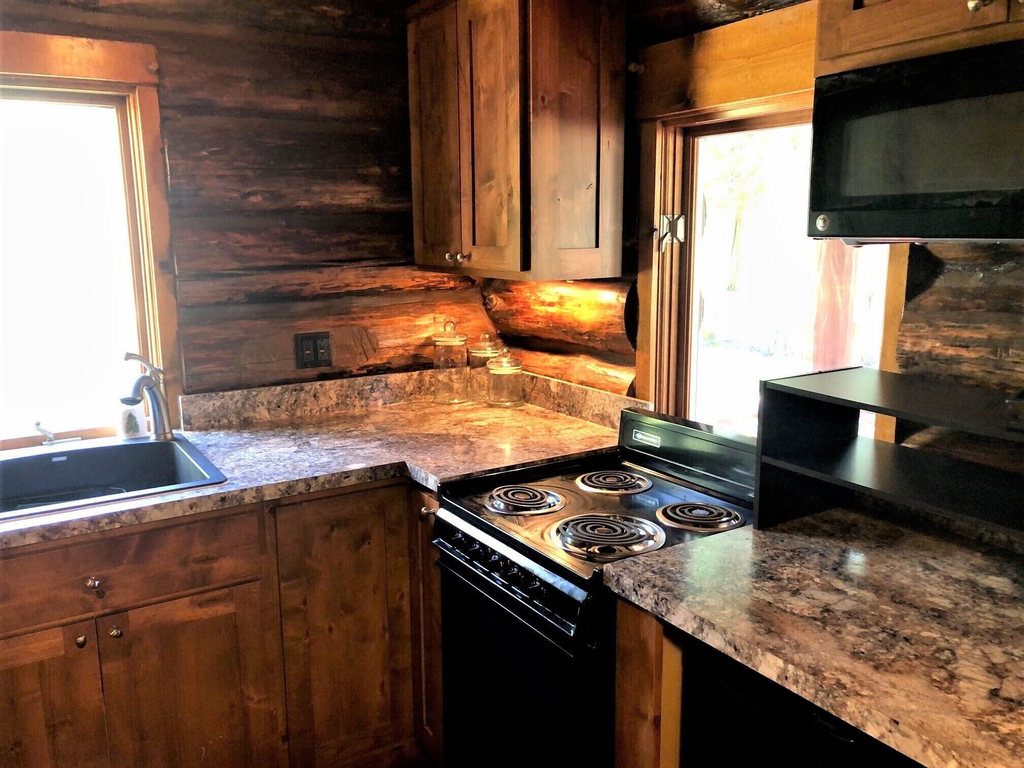 A kitchen with wooden cabinets, a granite countertop, a stove, and a microwave.