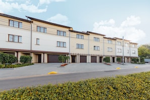 A multi-story building with a flat facade, multiple garage doors, and a paved driveway. - Arcadia Villa (Odesa)