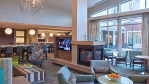 Eine moderne Hotelhalle mit Kamin, bequemen Sitzgelegenheiten, einem Fernseher und einer Bar.