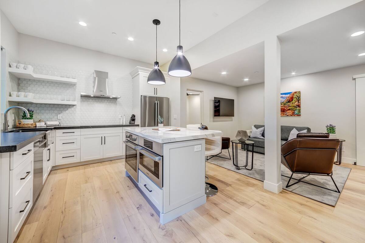 A modern kitchen with white cabinetry, a central island, and pendant lighting.