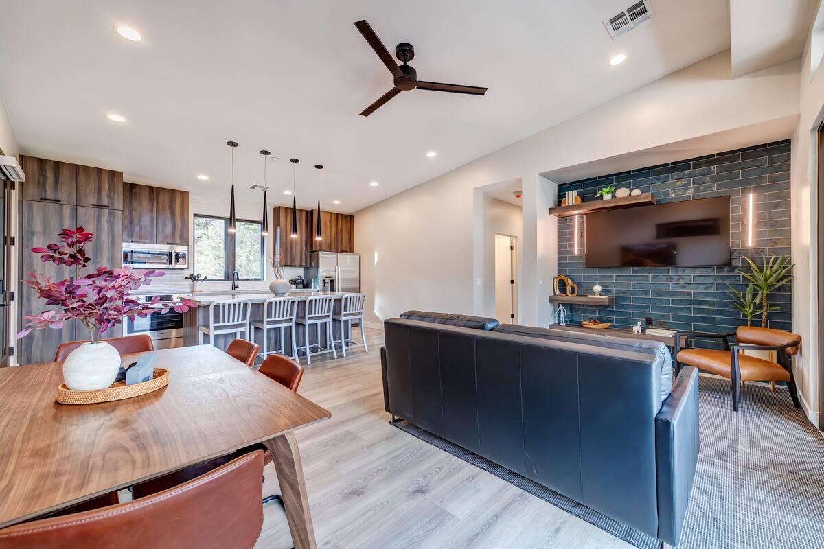A modern kitchen with a built-in oven, a dining area with a wooden table and chairs, and a seating area with a sofa and chairs.