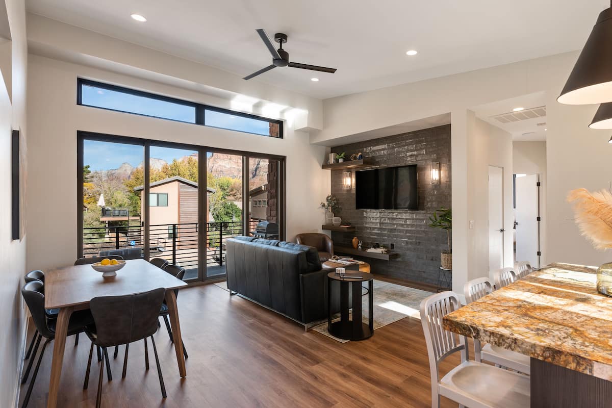 A spacious living area with a dining table, sofa, and a kitchen area with a TV and fireplace.