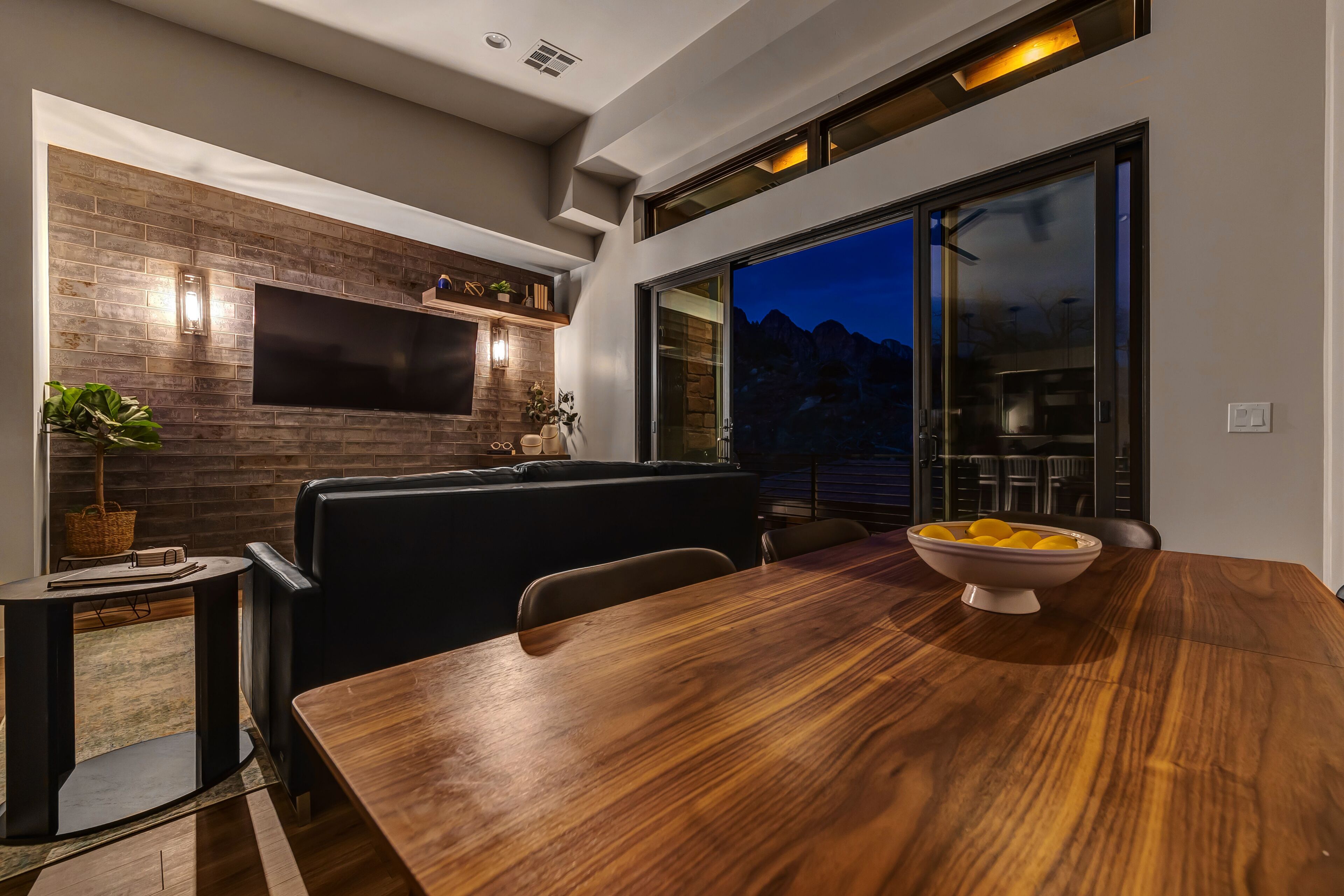 Une cuisine moderne dotée d’un téléviseur à écran plat, d’un revêtement mural en bois et d’un coin repas avec une table et des chaises en bois.