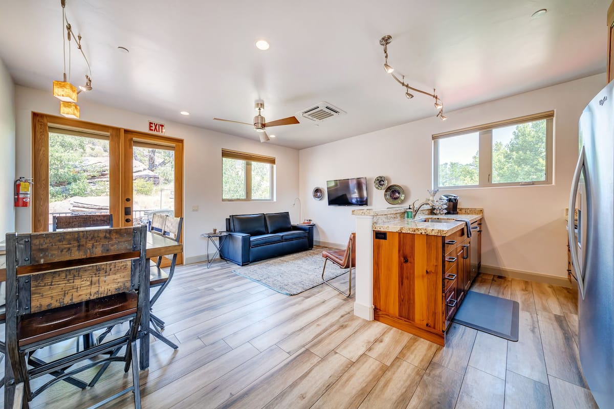 A spacious living area with a sofa, a wooden bench, a dining table, and a kitchen area with a refrigerator and sink.